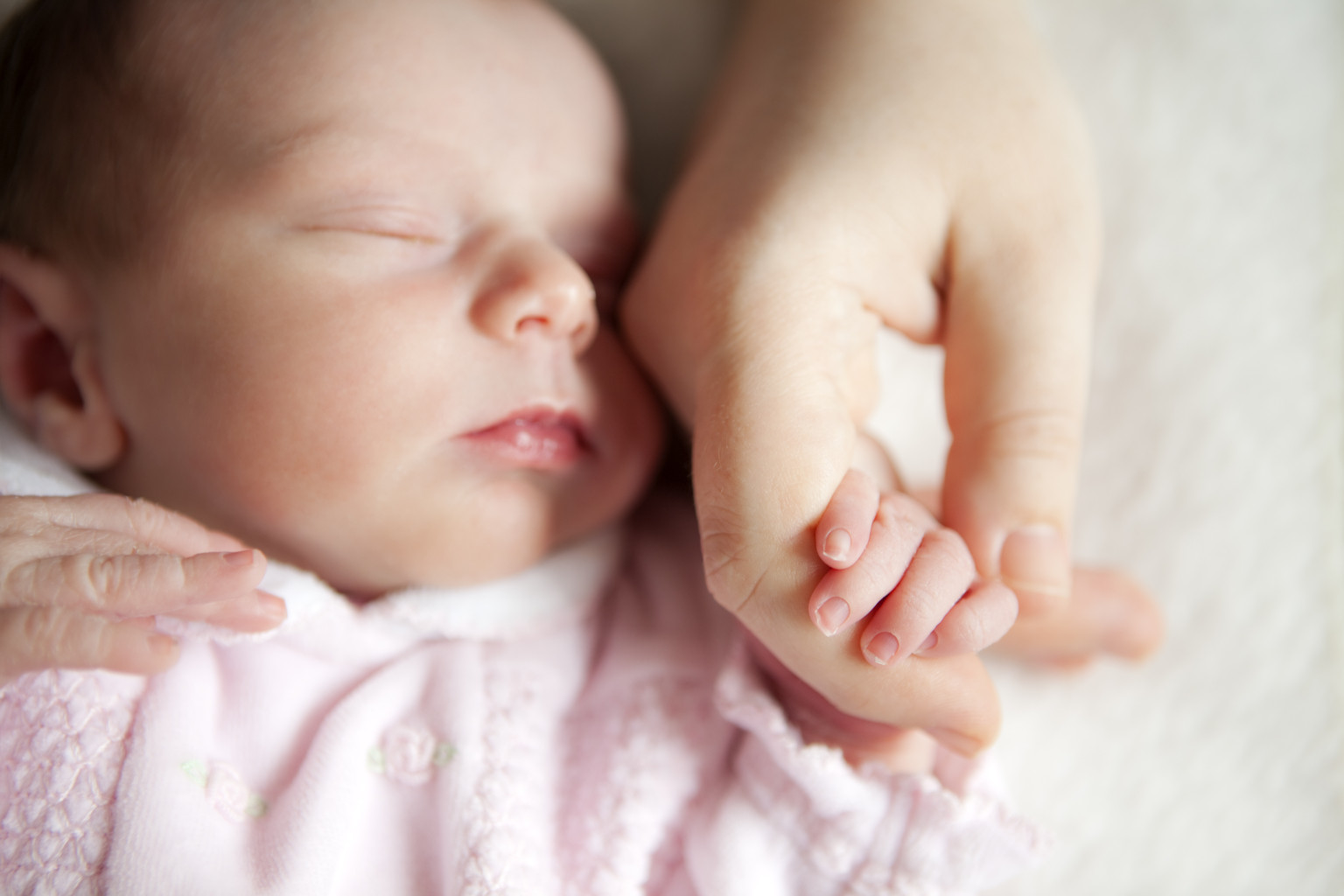 Newborn baby holding mother's hand